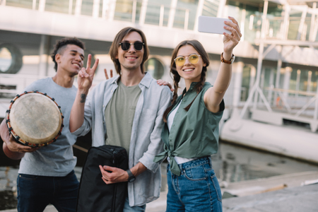 Young and happy street musicians with instruments taking selfie in cityの写真素材