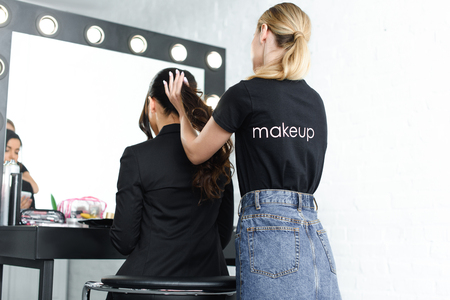 partial view of hairstylist doing hairstyle for businesswoman in suitの写真素材