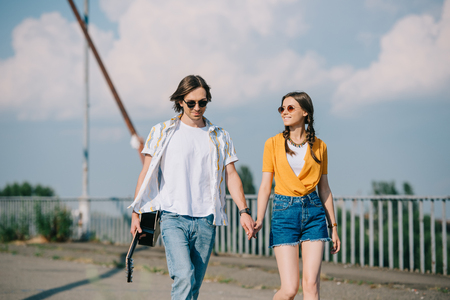 Young happy couple of buskers walking with guitar in hands at city streetの写真素材