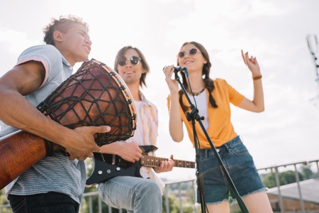 Young and happy street musicians playing music and singing in cityの写真素材