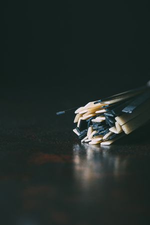 closeup shot of raw classical and black linguine pasta on black backgroundの写真素材