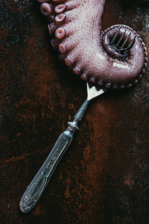 top view of big octopus tentacle with fork on rusty metal surfaceの写真素材