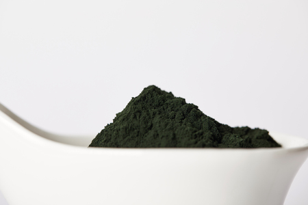 close up view of spirulina algae powder in bowl isolated on grey backgroundの写真素材