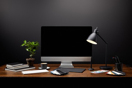close up view of graphic designer workplace with graphic tablet, blank computer screen, notebooks and pallet on wooden tabletopの写真素材