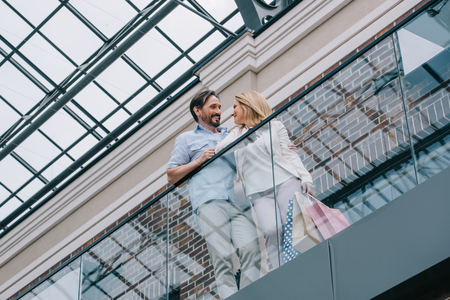 low angle view of couple standing on balcony in shopping mallの写真素材