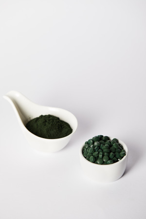 spirulina powder and spirulina pills in bowls on grey backgroundの写真素材