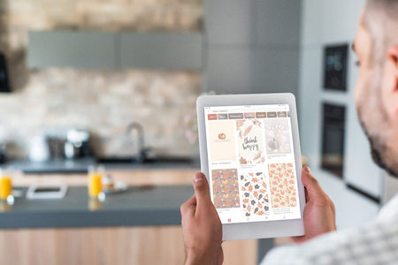 selective focus of man using digital tablet with pinterest website on screen in kitchen
