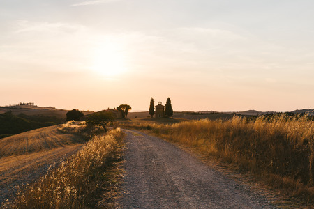 scenic view of beautiful Tuscany fields and empty road at sunset, Italyの写真素材