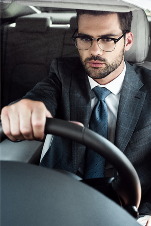 portrait of young businessman in eyeglasses driving carの写真素材