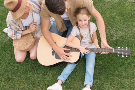 overhead view of family with one child playing acoustic guitar on meadowの写真素材