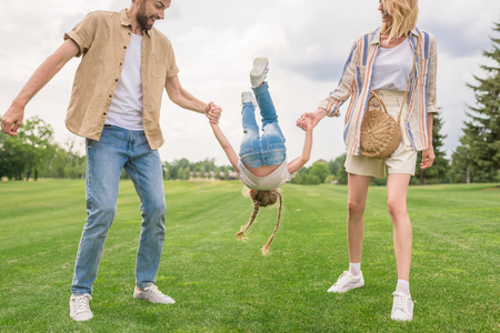 cropped shot of happy family with little daughter holding hands and having fun togetherの写真素材