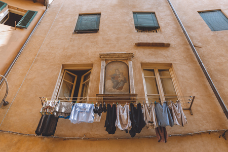 laundry hanging outside buildings with icon on wall in Pisa, Italyの写真素材