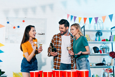 happy young friends playing beer pong at home partyの写真素材