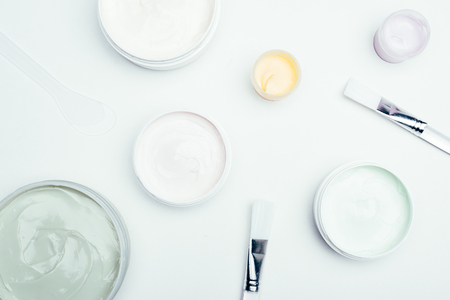 flat lay with different clay masks in containers and brushes isolated on white surfaceの写真素材