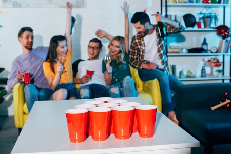close-up view of plastic cups and young friends having fun behindの写真素材