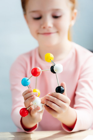 selective focus of smiling schoolchild holding molecular modelの写真素材