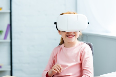 beautiful smiling redhead kid using virtual reality headset at homeの写真素材