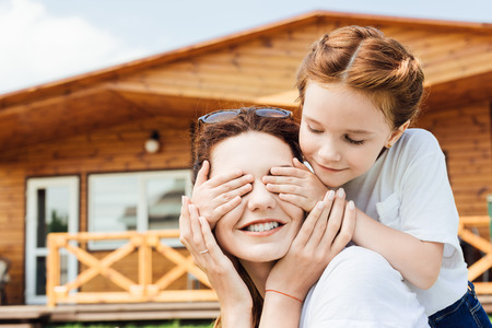 close-up portrait of daughter covering eyes of happy motherの写真素材