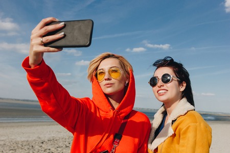 happy female friends taking selfie sandy beach, Saint michaels mount, Normandy, Franceの写真素材