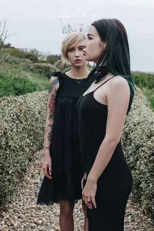 beautiful young women in black dresses in park on cloudy dayの写真素材