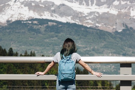 back view of girl with backpack looking at majestic scenic mountains, mont blanc, alpsの写真素材