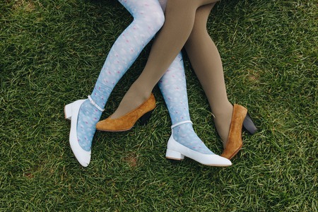low section view of girls in trendy shoes lying on green grass, Etretat, Normandy, France