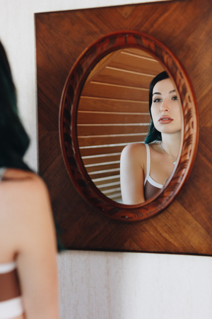 beautiful young woman in underwear looking at mirrorの写真素材