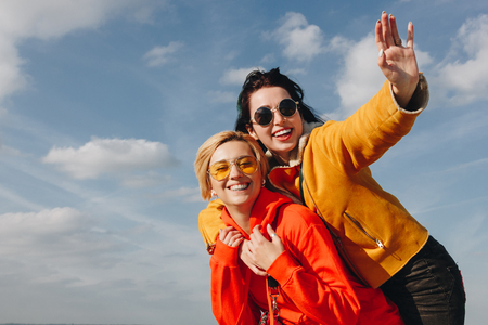 smiling girls piggybacking and waving in Saint michaels mount, Normandy, Franceの写真素材