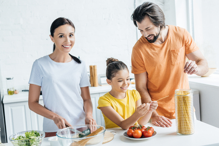 beautiful young family cooking healthy dinner together at kitchenの写真素材