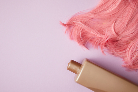 top view of bright pink wig and blank container on purpleの写真素材