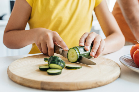 cropped shot of girl cutting cucumber with knifeの写真素材