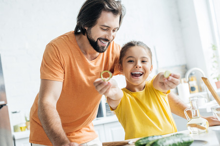 father and daughter having fun at kitchen while cookingの写真素材
