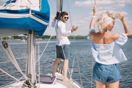 smiling young man in sunglasses looking at beautiful girl on yachtの写真素材