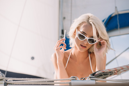 attractive woman in sunglasses talking on smartphone and laying on yachtの写真素材