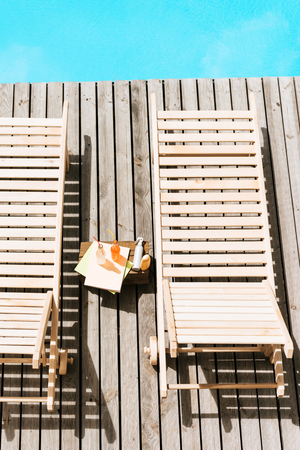 high angle view of empty chaise lounges and bottles with summer drinks near swimming poolの写真素材