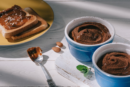 toast bread with chocolate and bowls with cocoa powder on white wooden tableの写真素材