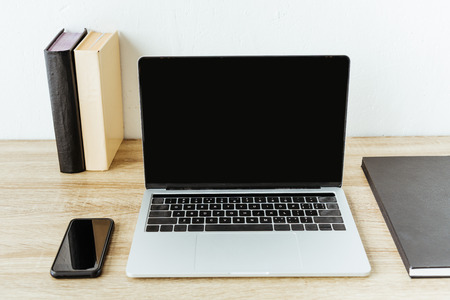 laptop with smartphone and books on work table at officeの写真素材