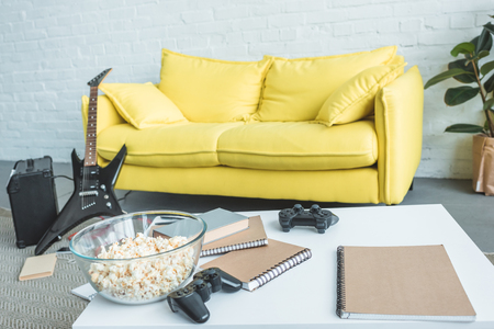 popcorn, joysticks and copybooks on table, electric guitar near couch behindの写真素材