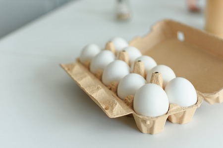close up view of raw chicken eggs in box on tabletop in kitchenの写真素材
