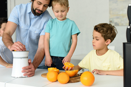 partial view of family making fresh orange juice together in kitchen at homeの写真素材