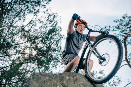 bottom view of young trial biker standing on rock outdoorsの写真素材