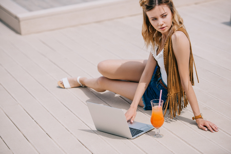 beautiful young woman using laptop and looking away outdoorsの写真素材