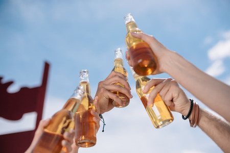 cropped shot of young people clinking beer bottles outdoorsの写真素材