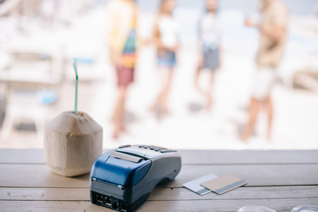 close-up view of summer cocktail with drinking straw and payment terminal with credit cards on bar...