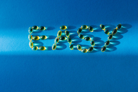 top view of lettering easy by pills on blue background with sunlightの写真素材
