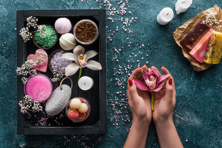 cropped shot of person holding orchid flower and organic spa accessories in boxの写真素材