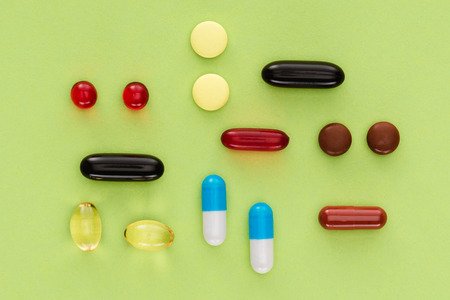 top view of arranged various pills on green backgroundの写真素材