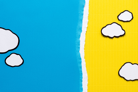 top view of paper clouds on blue and yellow paper backgroundの写真素材