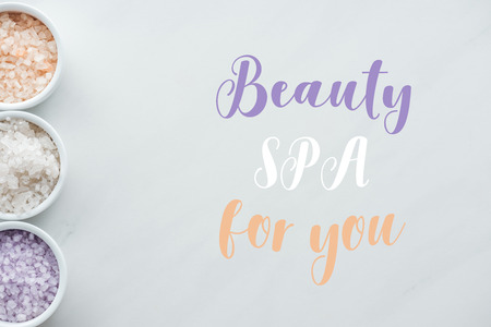 top view of sea salt in bowls and inscription beauty spa for you on whiteの写真素材