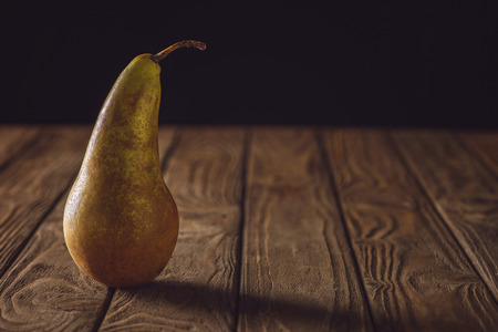 close-up shot of ripe pear on rustic wooden table on blackの写真素材